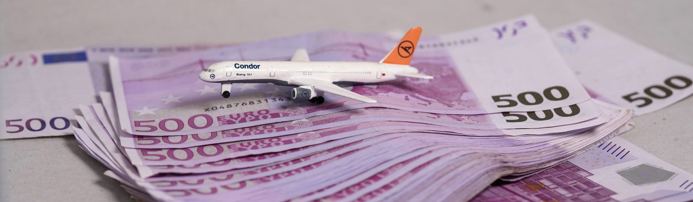 Viele Geldscheine, darauf ein Spielzeug-Flugzeug von Lufthansa